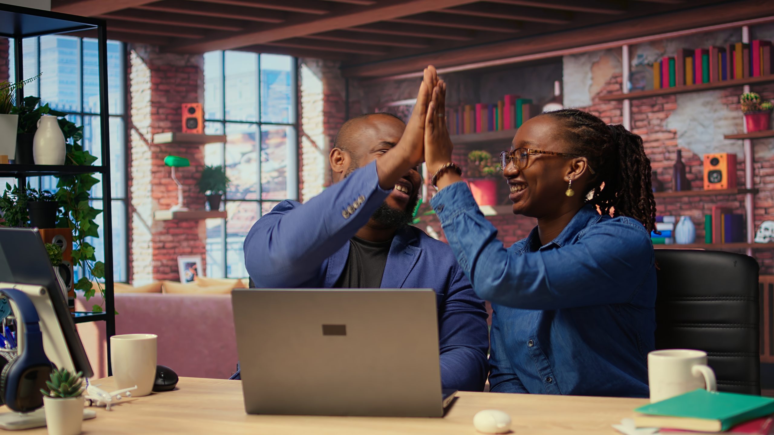 black freelancing couple doing a high five to celebrate their achievement